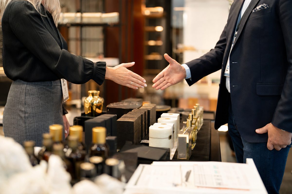 Wholesale trade show negotiation with product samples and buyer handshake